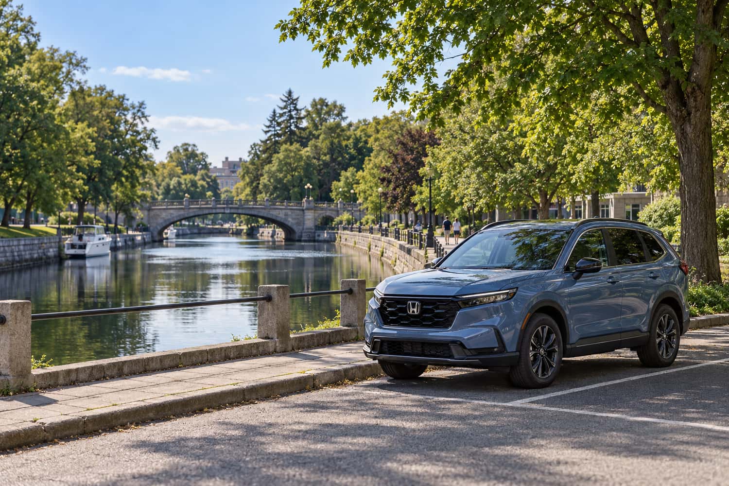 A blue Honda crossover parked beside a tree-lined canal, with a stone bridge in the distance
